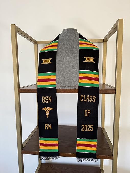 A black and yellow BSN RN Kente graduation stole featuring the bold vertical letters 'BSN RN' on the left, with a medical logo placed between 'BSN' and 'RN'. The phrase 'CLASS OF 2025' is embroidered horizontally on the right side of the stole. The stole showcases a custom Kente pattern with green, yellow, red, and green stripes, arranged in three sets on each side. The fabric is made of rayon.