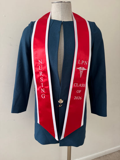 A Red With White Trim LPN graduation stole with royal blue trim, showcasing bold 'LPN ' lettering embroidered at the top, followed by a medical logo and 'CLASS OF 2026' embroidered beneath. The stole has slanted tips and a white plain background. All characters are embroidered.