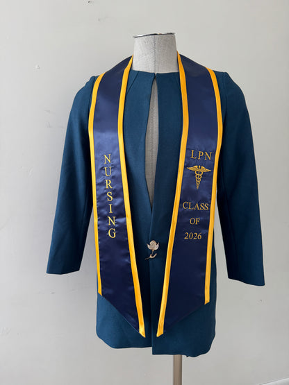 A Royal Blue With Gold Trim LPN graduation stole with royal blue trim, showcasing bold 'LPN ' lettering embroidered at the top, followed by a medical logo and 'CLASS OF 2026' embroidered beneath. The stole has slanted tips and a white plain background. All characters are embroidered.