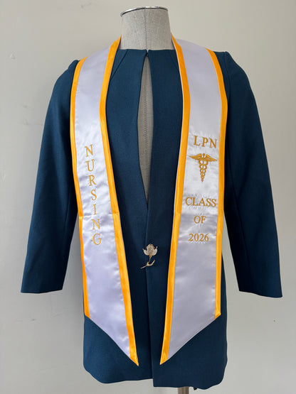 A White With Gold Trim LPN graduation stole with royal blue trim, showcasing bold 'LPN ' lettering embroidered at the top, followed by a medical logo and 'CLASS OF 2026' embroidered beneath. The stole has slanted tips and a white plain background. All characters are embroidered.